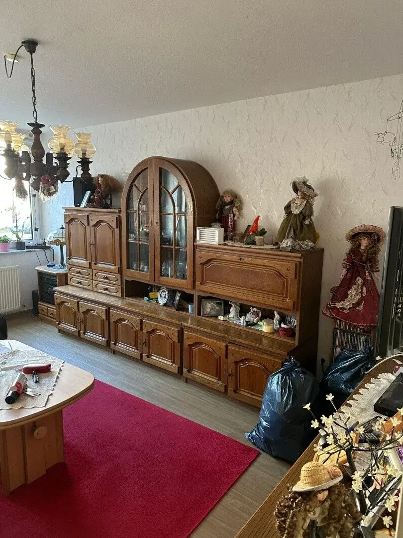 Wohnzimmer mit Holzschrank und Puppensammlung nach einer Entrümpelung